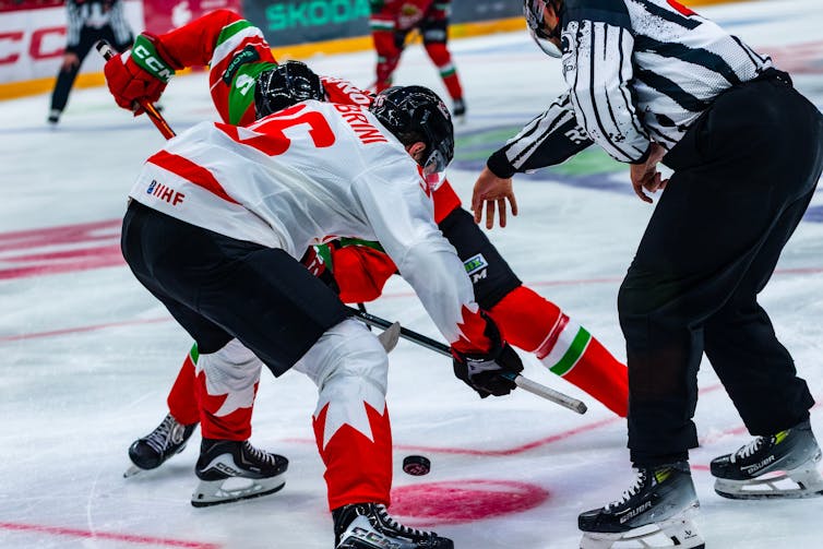 Ice hockey players face off against each other.