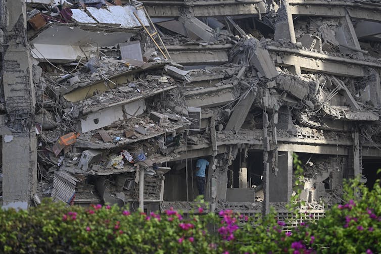 A man in a blue t-shirt enters a crumbling building.