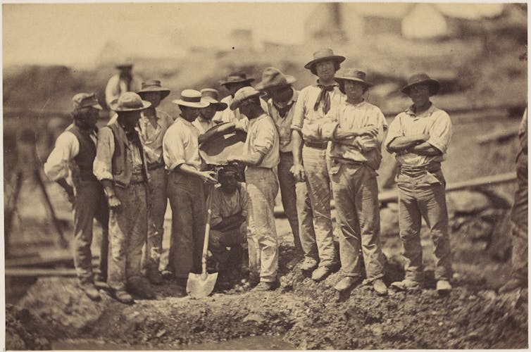 A historical black and white photo of a group of men prospecting for gold.