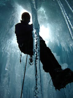 woman on ropes being hoisted down into icy crevass