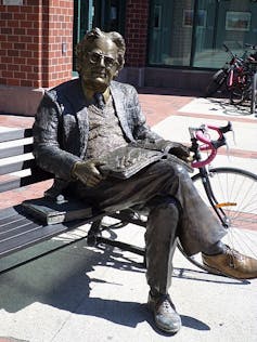 Statue of a man sitting on a park bench.