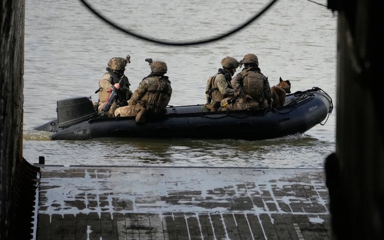 Soldiers in combat gear in a rubber dinghy.