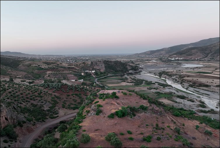 A panoramic view of a vast valley with hills in the distance and rivers running through it.