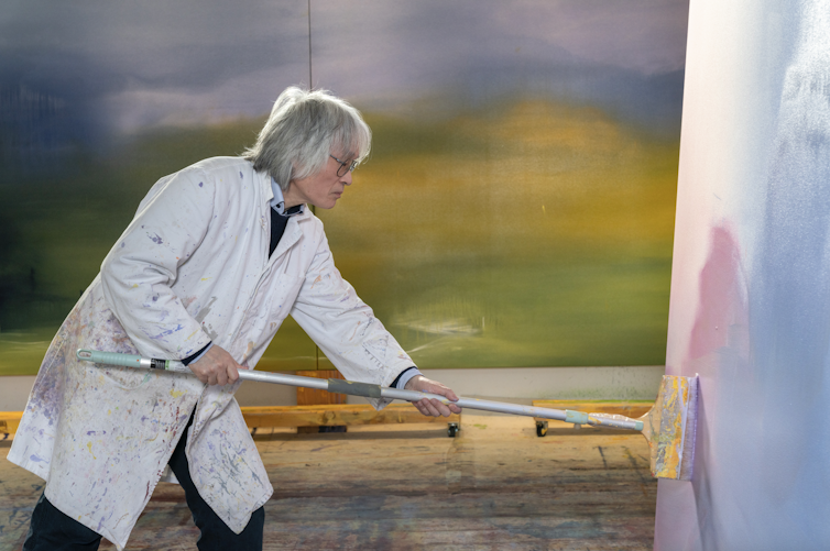 Feng Xiao-Min working on a painting with a long-handled brush