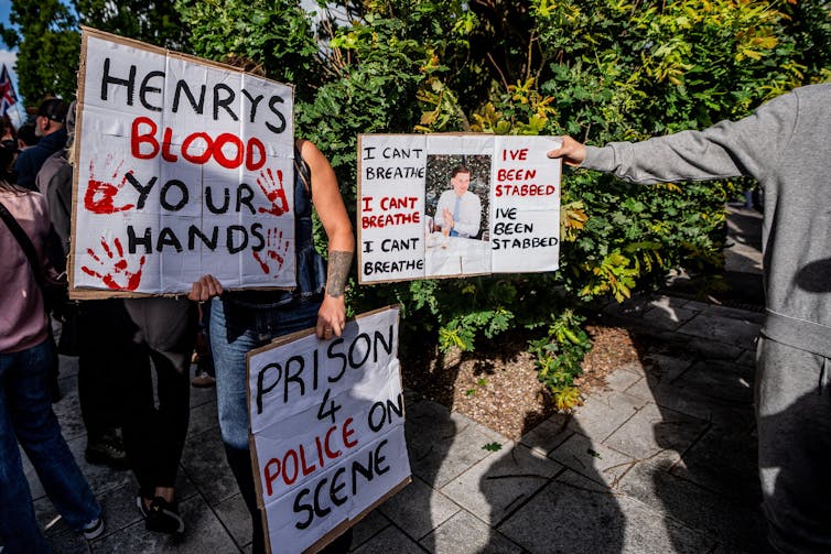 Protest signs calling for prison for police and reading 'henry's blood is on your hands'