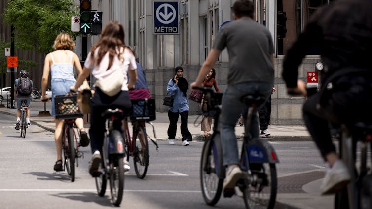 people of bicycles ride along a road in a city