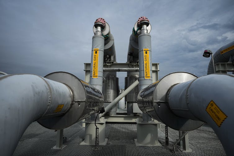 Wide, curved silver pipes with yellow signs reading Natural Gas
