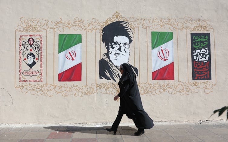 A woman walks past a mural of Iran's late former supreme leader, Ali Khamenei.