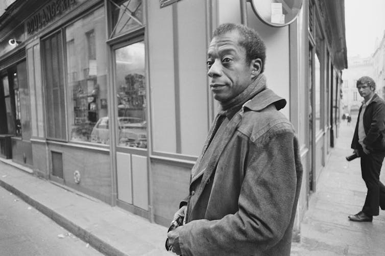 A Black man on a street in Paris in an overcoat