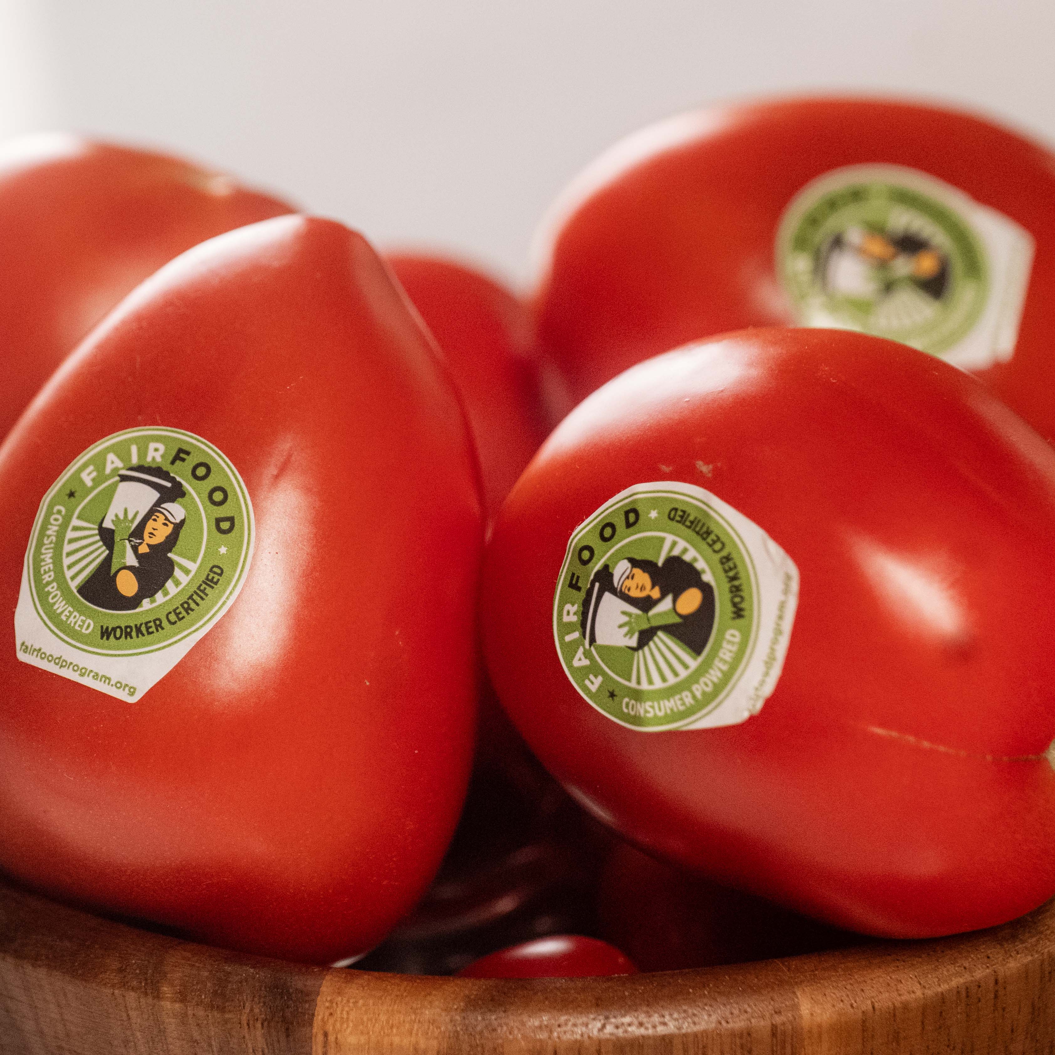 Tomatoes with “Fair Food” stickers in a wooden bowl.