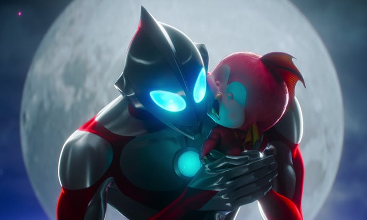 An animated silver and red giant robot holds a red baby robot.