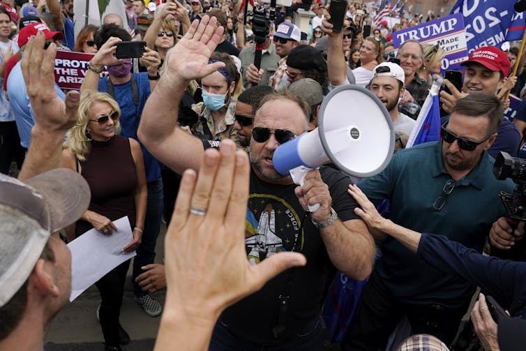 a man with a megaphone surrounded by supporters