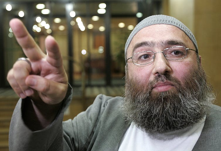 a man in Islamic dress with two fingers raised