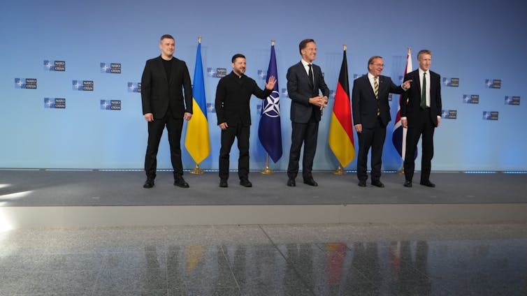 A row of men stand on a stage.