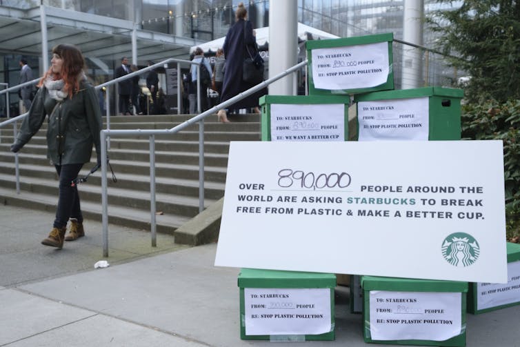 A woman passes a display set up by activists takin aim at Starbucks packaging policies.