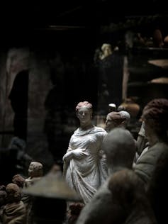 A Roman statue sits in a dimly lit museum.