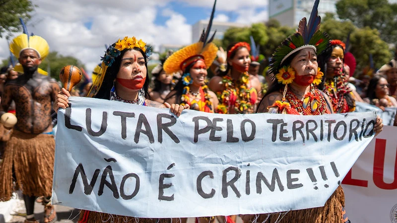 Indigenous women carry a banner saying: "Fighting for territory is not a crime"