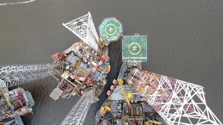 aerial shot looking down at oil rig, helicopter pads and grey ocean