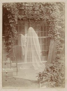 A sepia photograph showing a classic ghost-in-a-sheet figure