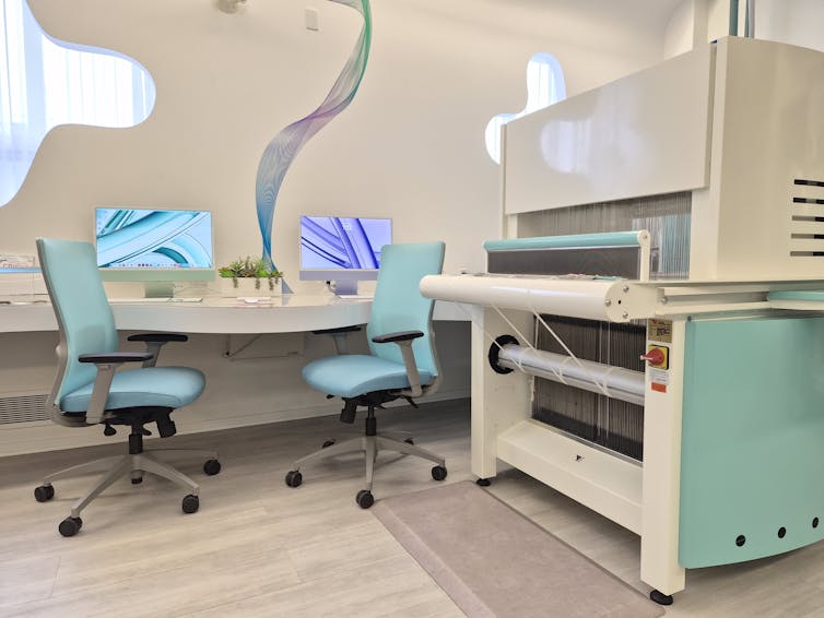 A digital loom in a research lab with a computer desk showing the software that controls its parametric design