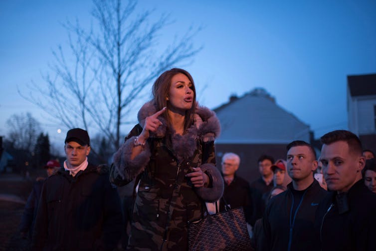 a woman with dark hair speaks at an outdoor event