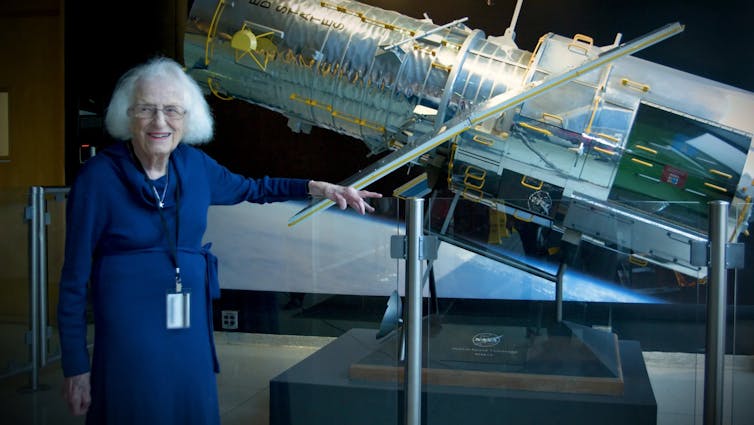 Nancy Grace Roman stands next to a scale model of the Hubble Space Telescope outside the Hubble control center at Goddard Space Flight Center in Greenbelt, Maryland.