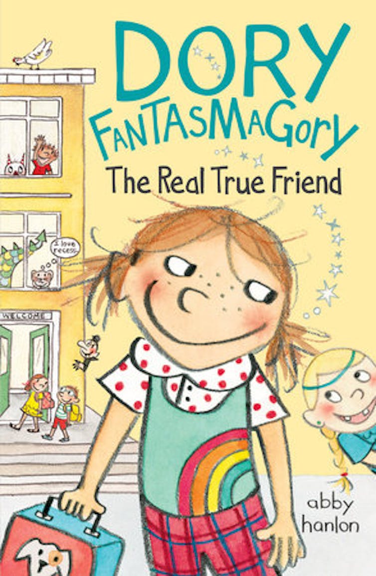 A pale yellow book cover says 'Dory Fantasmagory The Real True Friend' and shows a cartoon image of a young girl in a green shirt with a rainbow on it, in front of a building with people and cartoon characters coming out of its doors and windows.
