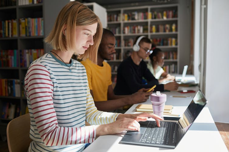 a young woman using a laptop at a library.
