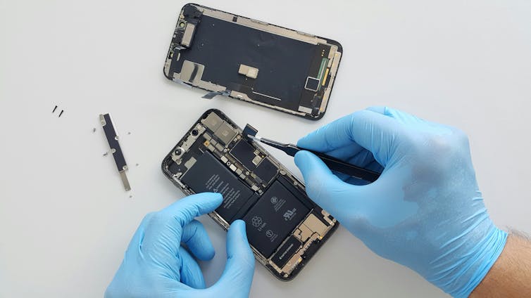 A smarthphone with the back taken off is being repaired.