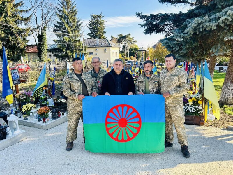 A photo of Roma soldiers in the Ukrainian Armed Forces holding a Roma flag alongside Ukrainian flags.