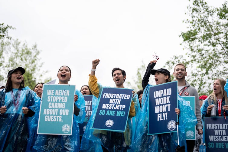 People chant while holding signs in support of a strike against unpaid flight attendant labour