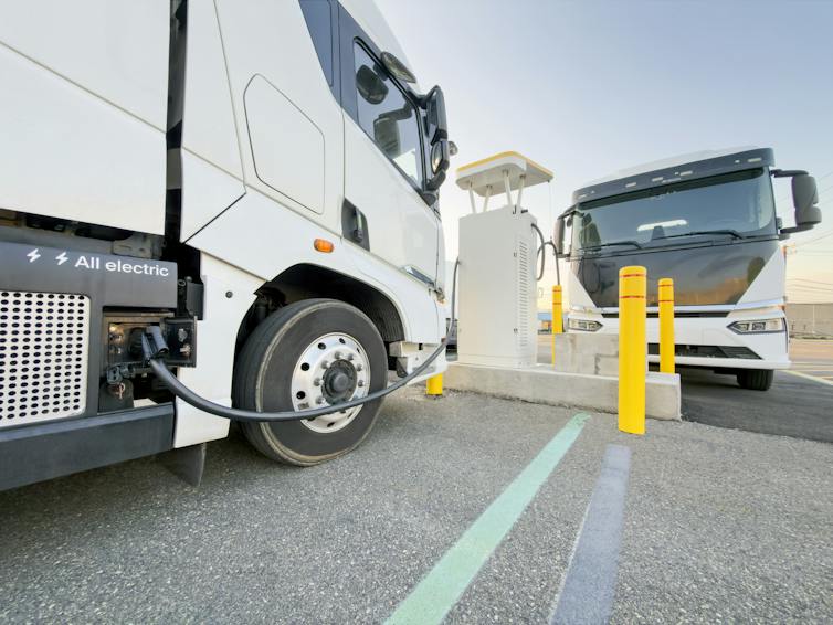 Two electric trucks charging at a commercial EV charging station