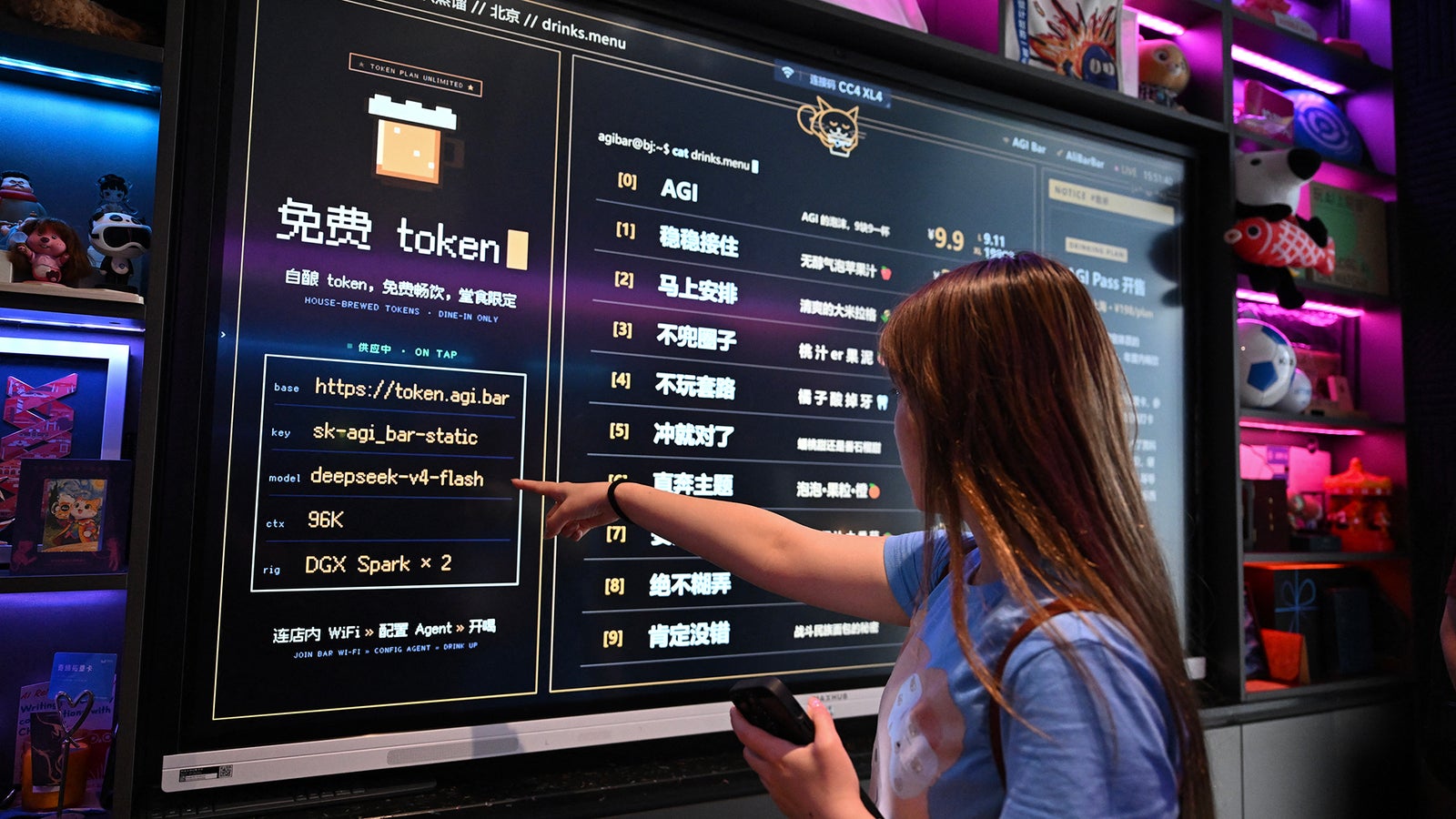 A woman points at a digital menu board displaying drink options and QR code information at a bar with colorful decor