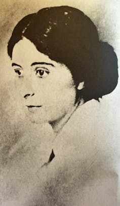 Portrait of a woman in half-profile, with her hair tied back.