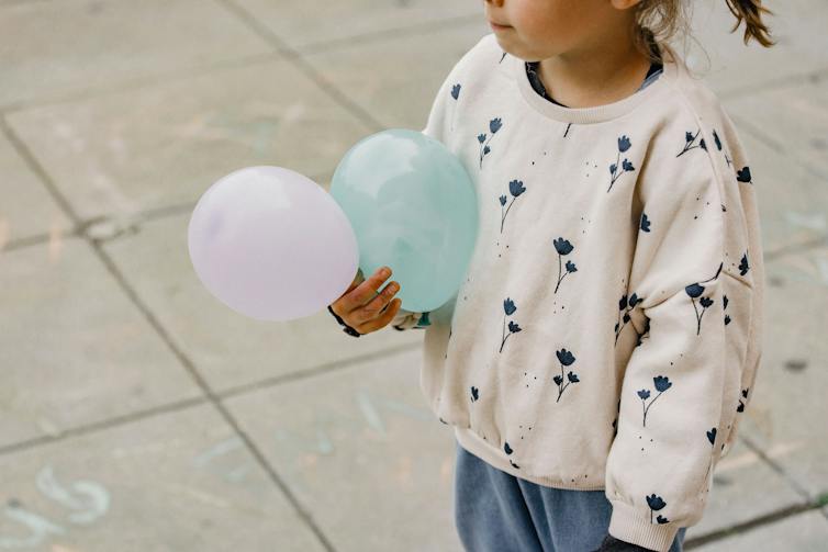 A girl holding two balloons.