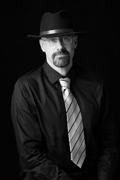 The author: a man in a black shirt, tie and a black cowboy hat.