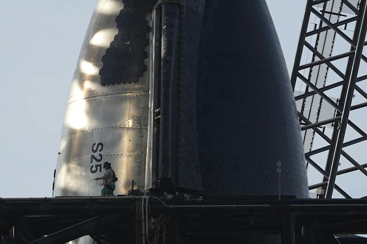 A close of up the tip of the Starship rocket, which looks like a cone, with one side covered in a grid of hexagonal tiles.