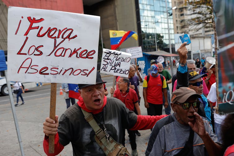 Protesters seen holding signs and Venezuelan flags.