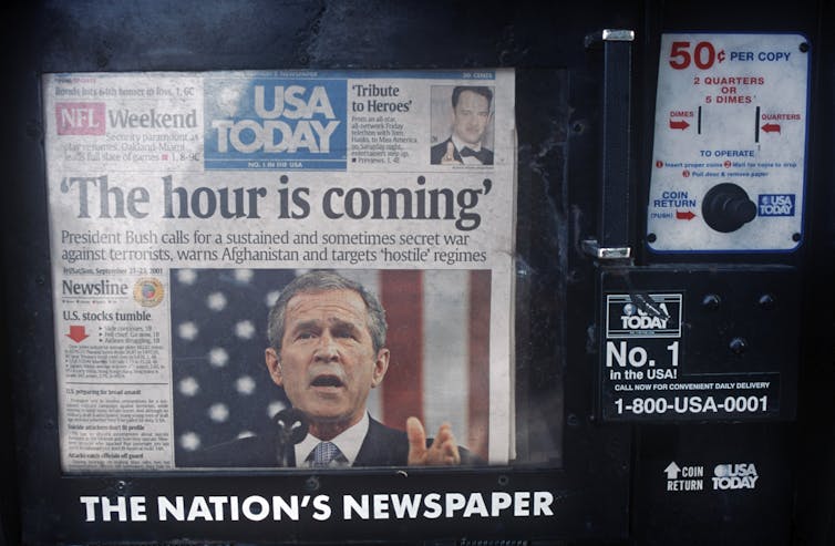 A newspaper box with a newspaper inside whose front page headline reads 'The hour is coming' and a photo of President George W. Bush.
