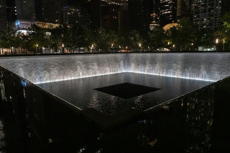 Nighttime view of reflecting pools with waterfalls in the footprint of the Twin Towers.