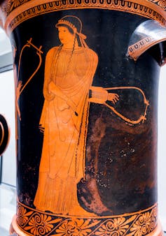 A figure holding a musical instrument gazing to the side.
