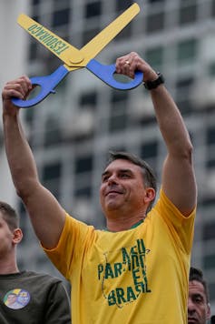 Opposition presidential candidate Flavio Bolsonaro holds up a pair of symbolic scissors with the word tesourão, Portuguese for 'big scissors'.