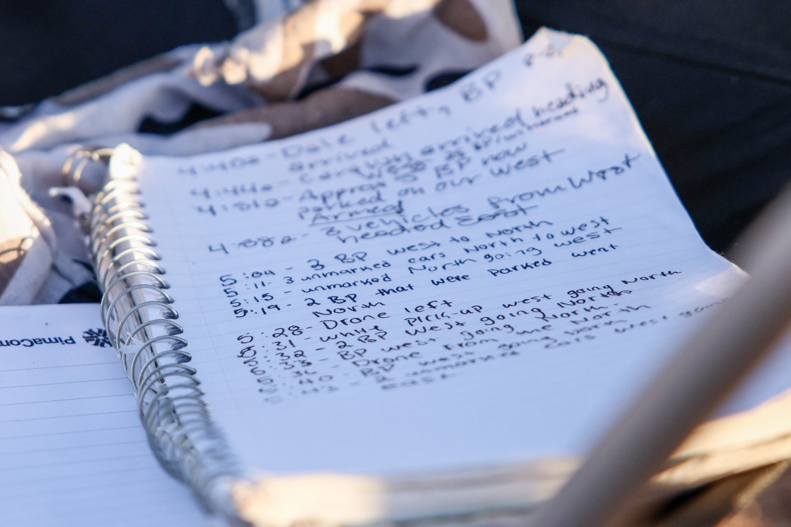 A lined white notebook page containing log entries tracking Border Patrol movements and surveillance sits on a table.