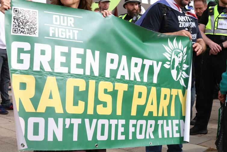 Protestors outside the Green party conference with a banner saying the party is racist
