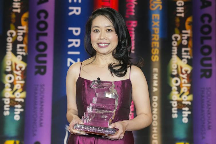 A woman in a glittering dress stands in front of a display of books
