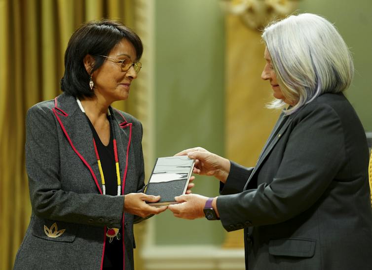 A woman receives an award from another woman.