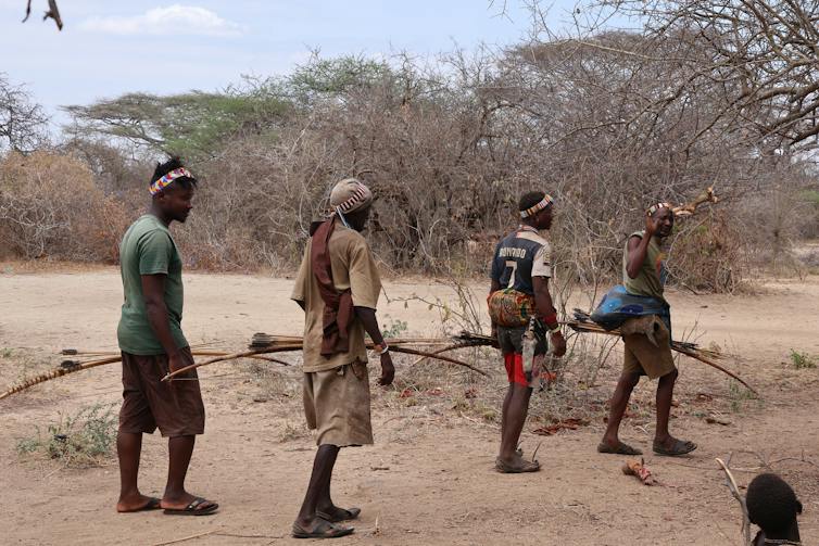 four men with bows walking in a dry landscape