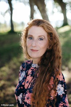 A woman with long red hair and a floral dress