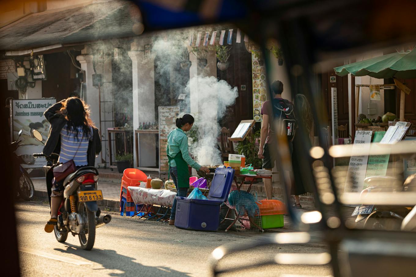 Street market with steaming food stalls and motorbik in Laos