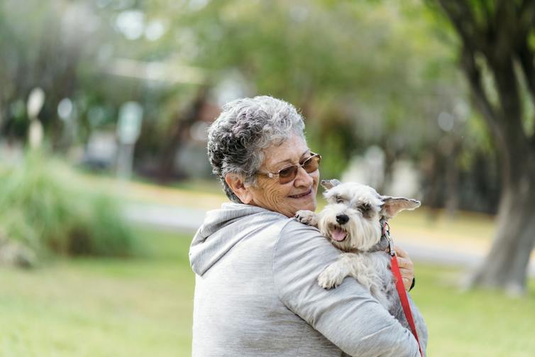 Older adult holding dog in park